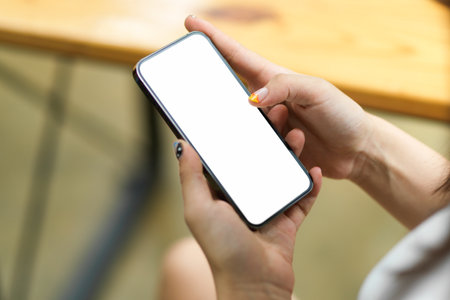 Close up of female hands browsing, using, paying, holding on smartphone with blank screen, blurred backgroundの写真素材