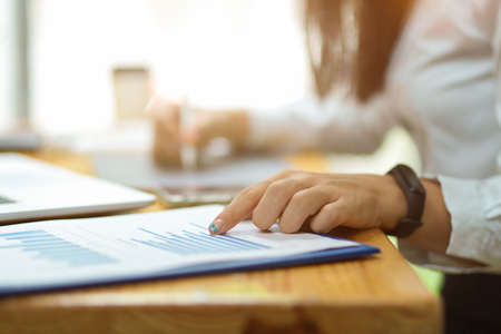 Cropped shot of female finger pointing on financial papers with blurred in the background