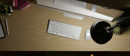 Top view dark work space with desktop computer, headphone, table lamp and plants on wooden desk,...
