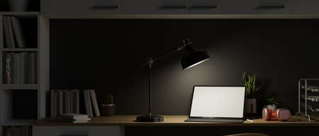 Work space at night with open laptop and light from table lamp, late night working, dark work space, modern home office interior decor, 3d rendering, 3d illustrationの写真素材