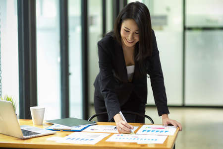 Business female worker preparing business report for meeting, checking statistic graphs, at officeの写真素材