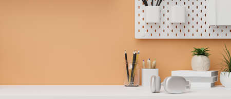 Pastel orange wall with white shelf, stationery, headphone and indoor plants on white desk with empty space for your product display, 3d rendering, 3d illustrationの写真素材