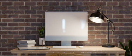 Modern home work space in red brick wall with low light from table lamp, computer and frame mock up, industrial loft style, 3d rendering, 3d illustrationの写真素材