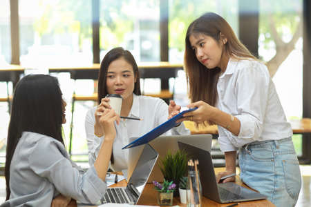 Group of college student discuss about their work assignment at coffee shop, laptop, coffee, report and decor, brainstormingの写真素材