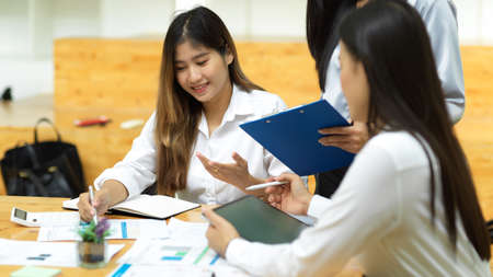 Asian business team consulting about company loan comparison together at office with reports, tablet on wood tableの写真素材