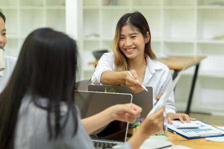 Asian female business team talking and voting for next business campaign, female worker pointing at the paper, at office, brainstormingの写真素材