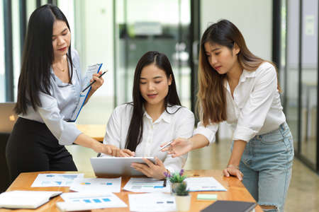 Young female business team discussing and analysing their project before meeting at officeの写真素材
