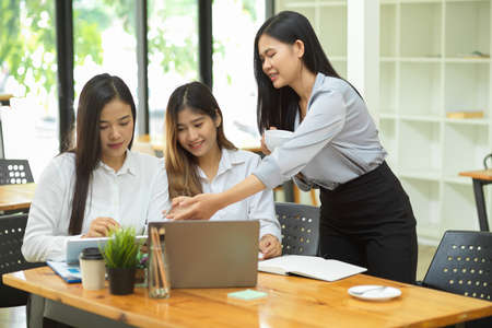 Young business group discuss and summarise the financial data on tablet with laptop and reports on wood table at office roomの写真素材