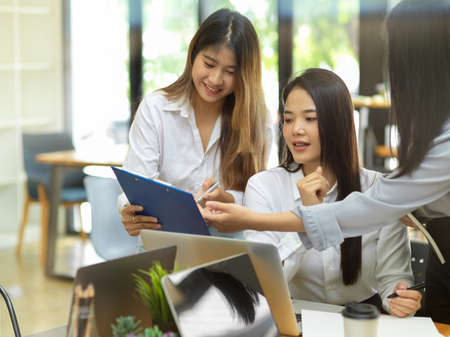 Business worker showing the data report to her colleague at office room, laptop, happy to work together, smiling, brainstormingの写真素材