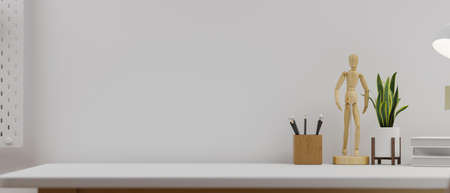 Minimalistic working space with bright decor interior, white wall, copy space on table, wood figure, plant in pot, pencils, 3d rendering, 3d illustrationの写真素材