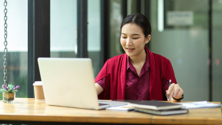 Costing manager working on laptop with lots of paperworks on her desk at office, busy businesswoman conceptの写真素材