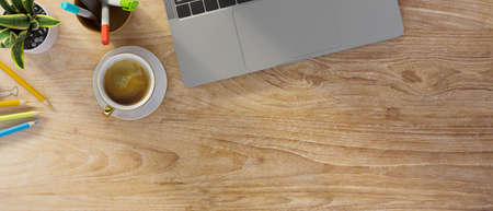 Wooden background with laptop keyboard, coffee, stationery, small plant in pot and copy space for...