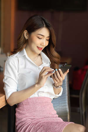 Attractive young female entrepreneur reading business content on her smartphone, browsing internetの写真素材