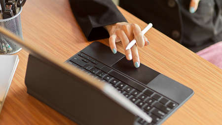 Digital tablet on wood table, business female scrolling on tablet, surfing the net, close up