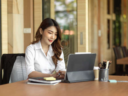 Secretary of executive manager checking her boss schedule on digital tablet at her office desk, working on tabletの写真素材