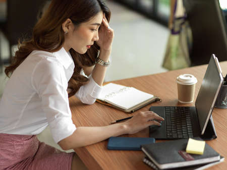 Pensive businesswoman thinking important business decision, solve business problems at office, smart tablet, office suppliesの写真素材
