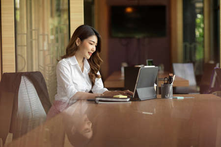 Millennial businesswoman manager negotiate business import product with supplier via digital tablet at officeの写真素材