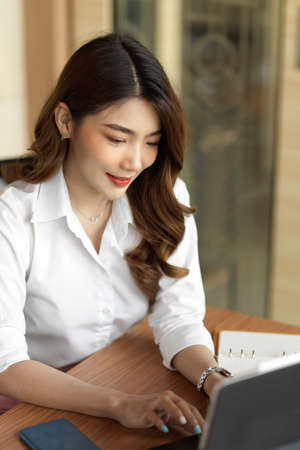 Confident businesswoman using tablet computer to work at office, girl typing on tablet keyboard, portraitの写真素材