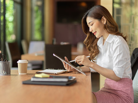 Businesswoman checking stock from digital tablet, list advertising idea on tablet at office working deskの写真素材