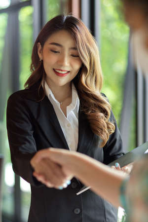 Businesswoman shaking hand with her business client at office, business negotiationsの写真素材