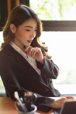 Portrait of elegant young professional  businesswoman sitting and pondering, thinking, working to create new business ideaの写真素材