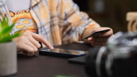 Cropped shot of freelance photographer using smartphone and holding credit card to pay accommodation loan via online applicationの写真素材