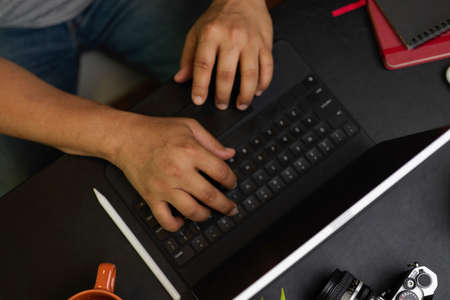 Overhead layout, businessman in casual looks working on weekend at coffee shop, typing on portable tablet, black backgroundの写真素材