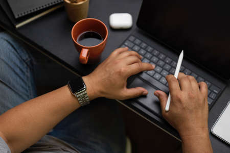 Close up, businessman typing on portable tablet, male trader analyse data at modern co-working space