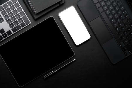 Office black leather workspace with wireless gadget, black screen tablet, white screen smartphone...