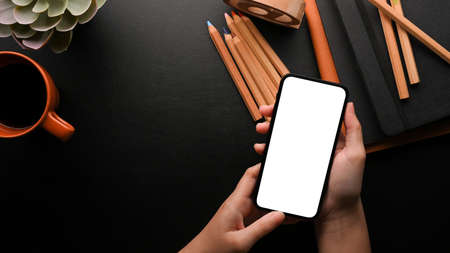Top view, people are using smartphone for work on modern office desk, close up hands, copy space on...