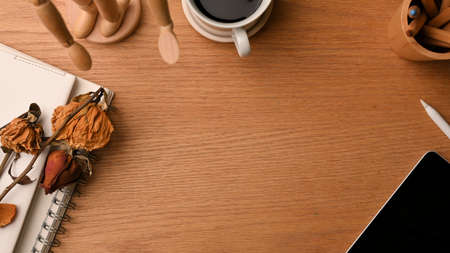 Simple work space with copy space on wooden background surrounded by stylish decorations, wood figure, dry flowers, coffee, tablet, pencils, notebook, autumn workspace concept, close up, flat layの写真素材