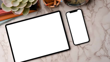 Two devices in flat layout, smart tablet and smartphone mockup, blank screen for your brands, on marble background, workspace decorationsの写真素材