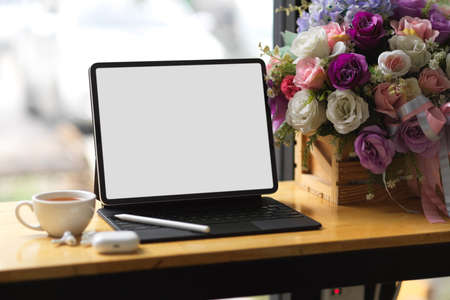 Close up, tablet with keyboard on wood table , empty screen mockup, a cup of tea, working at co-working space conceptの写真素材