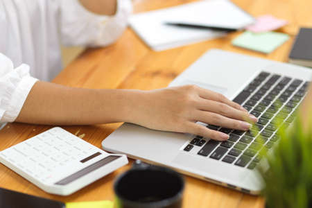 Close up, female college student doing her accounting assignment on laptop, typing on laptop keyboard at weekendの写真素材