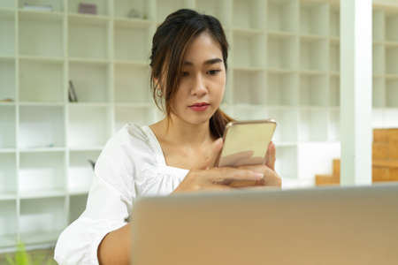 Young asian female sending message via smartphone, browsing business information, chattingの写真素材
