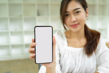 Focused smartphone blank screen mockup holding by beautiful female, spacer your advertisementの写真素材
