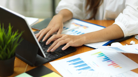 Closeup businesswoman hands , working with smart tablet and financial documents, filling form on tablet, officeの写真素材