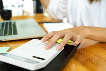 Close up fingers, woman calculating household expense, pay bills, using calculator, workspaceの写真素材