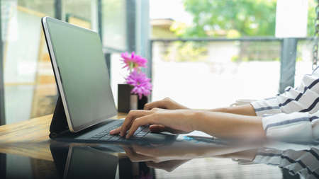 Side view, closeup hands typing on tablet keyboard, blurred background, business worker, freelancerの写真素材