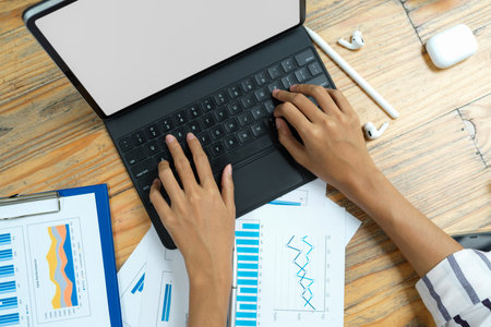 Top view of businesswoman hands typing on laptop, analysing graph, work from home, blank screen laptop mockupの写真素材