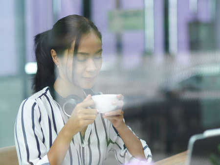Image of female freelancer holding coffee cup, smelling coffee in the morning, relaxationの写真素材