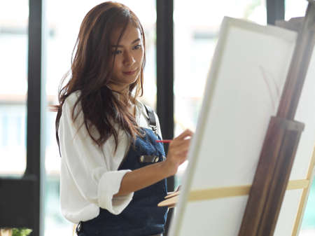 Female painter painting artwork on canvas easel, attractive female artist, creative personの写真素材