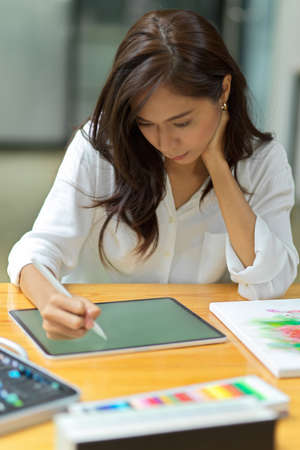 Beautiful female graphic designer working on digital tablet, inspired art work, sketching plans at...