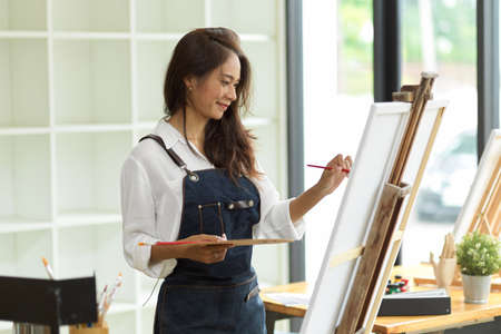Attractive young woman attending a painting workshop, having fun, create an inspired art work at art studioの写真素材