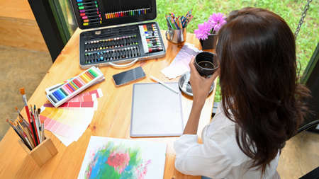 Top view of graphic art designer, creative desk, digital tablet with painting tools, colour pencils,...