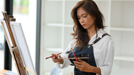 Female artist painting art on canvas at studio, designing colour for artwork, inspirationの写真素材