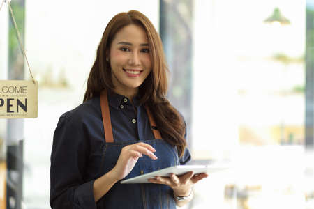 Beautiful barista image, female barista using portable tablet taking order from customer, coffee shop staffの写真素材
