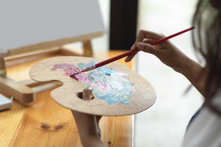 Closeup, female artist mixed oil colour on art palette, creative activity, painting on canvasの写真素材