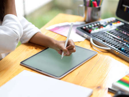 Closeup, graphic designer using stylus pen sketching new prototype on digital tablet at office, tablet blank screen mockupの写真素材