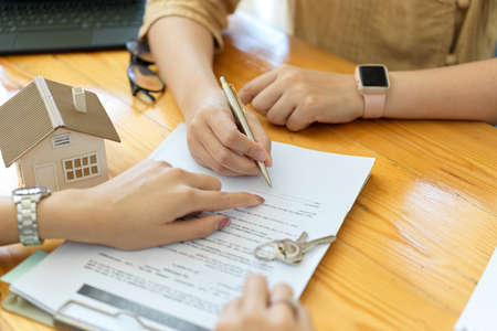 Real estate agent doing contract with new client, signing house insurance, rent house, investmentの写真素材